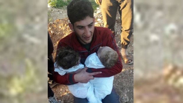 A man holds his twin toddlers who were killed during the chemical weapons attack in Syria.