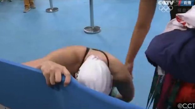 Chinese swimmer Fu Yuanhui crouching in pain after the race.