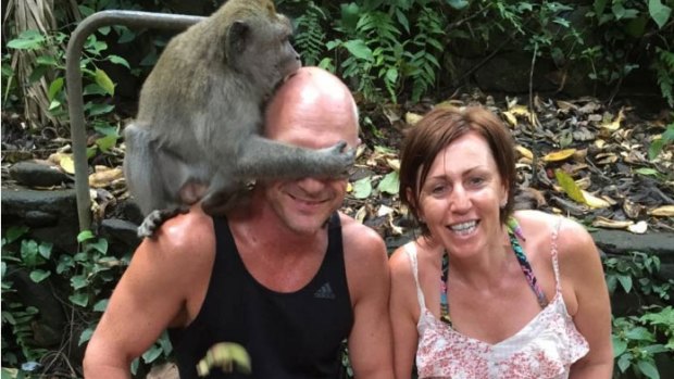 A monkey bites Anthony Wallace on the head as he sits next to girlfriend Libby McManus at Ubud Monkey Forest in Bali.