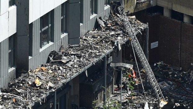 A firefighter holds a riot shield above his head to avoid debris as he enters the building.