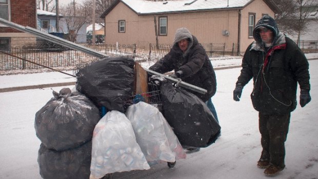 A pair of scrappers fight blizzard conditions to deliver their haul of aluminium cans to the scrapyard. They may earn $30 to $50 for the lot.