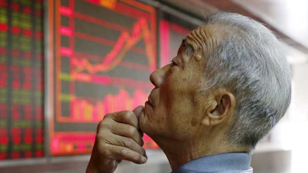 An investor watches an electronic board showing stock information at a brokerage office in Beijing.