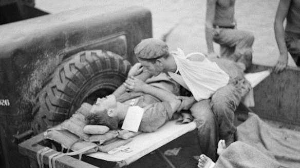 A soldier comforts his shell-shocked friend while they wait to be evacuated from Papua New Guinea during World War II.
