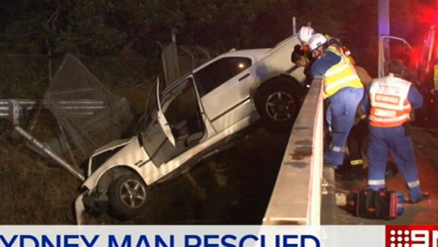 A man fell 10 metres onto train tracks after trying to climb out of his car.