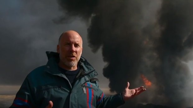 Michael Bachelard in front of a burning oil well near Mosul.