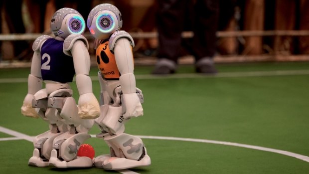 A robot from the Australian UNSW team (right) faces off with a German opposition player for the ball.