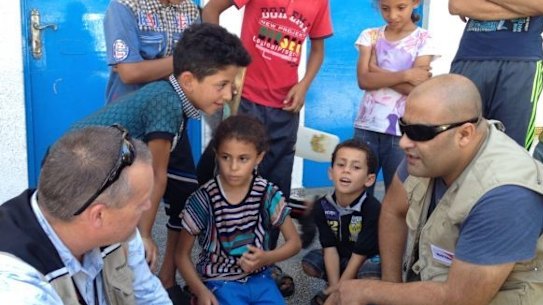 Mohammed Al Halabi, right, is seen talking to children in his work as Gaza program manager for World Vision.