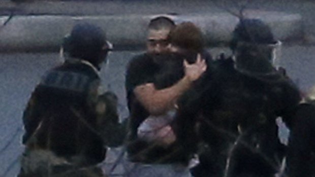 Hostages, including a small child, are led from the supermarket.