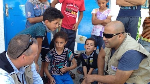 Mohammed Al Halabi, right, is seen talking to children in his work as Gaza program manager for World Vision.
