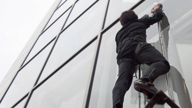 Elliot Hawkes scales a glass wall during a test of the 'gecko gloves'.