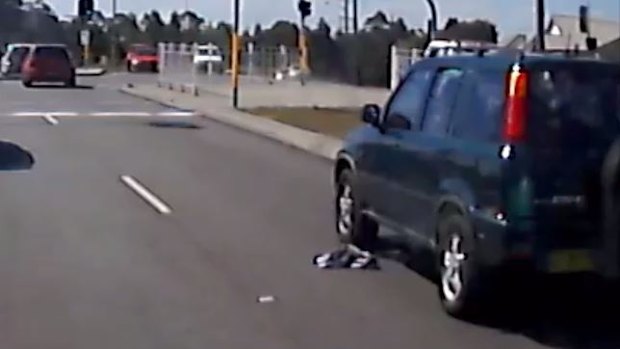 A discarded shirt remains on the road as traffic begins to drive away.