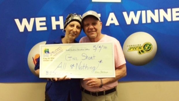 Gina Short brandishes her lottery cheque with her husband Len.