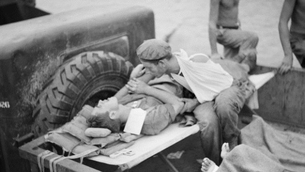 A soldier comforts his shell-shocked friend while they wait to be evacuated from Papua New Guinea during World War II.