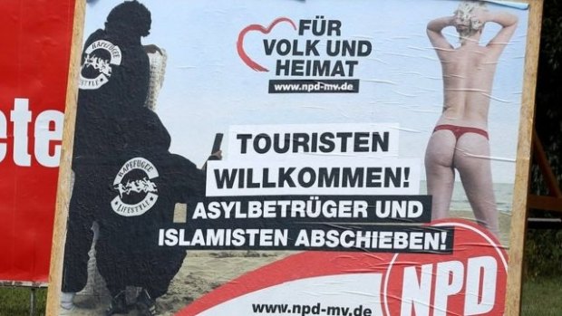 A poster of Germany's far-right NPD in which 'rapefugees' take photos of a beachgoer: "Tourists welcome - asylum cheaters and Islamists out!" 