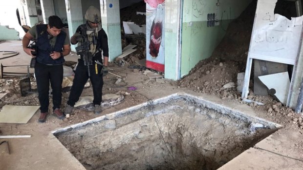 A soldier with Iraq's elite counterterrorism force, left, inspects a tunnel made by Islamic State militants in Bartella, Iraq, about 20 kilometres east of Mosul on Thursday.