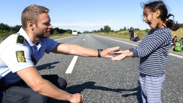 This image of a Danish police officer playing with a Syrian refugee has gone viral online.