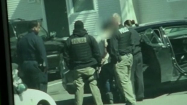 Police detain a suspect outside the Detroit home where two children were found in a freezer.