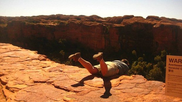 A guide poses next to a warning sign at Kings Canyon.