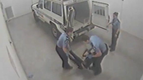 Ms Dhu being loaded into the back of a police van.