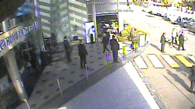 The scene: Denis Fitzgerald (third from left in white shirt) outside Parramatta Leagues Club while security staff try to talk David Zaiter off the road on Thursday.
