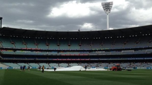 Clouds gather over the MCG as the covers are rolled over the pitch.