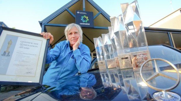 Filmmaker David Bradbury pauses outside the Brunswick Heads Centrelink office, with his Mercedes and awards. 
