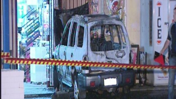 The burnt out vehicle in front of a Middle Swan bottle shop where it became stuck on bollards.