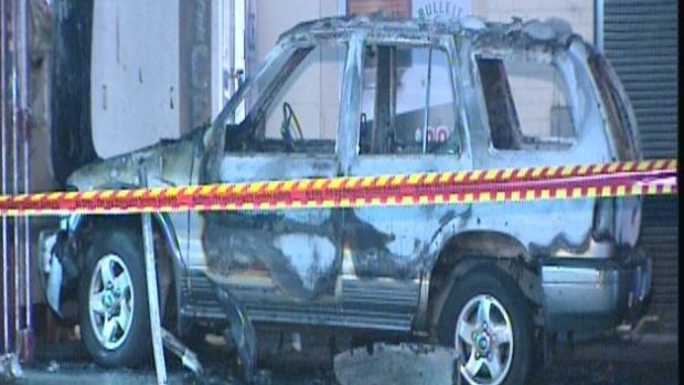 The burnt out vehicle in front of a Middle Swan bottle shop where it became stuck on bollards.