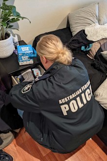 An AFP officer searches through the bedside drawers of a Willoughby man.