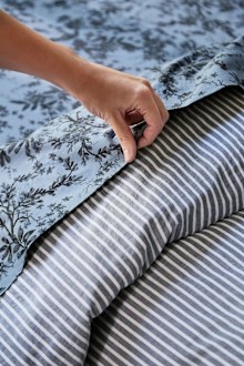 Floral bed sheet paired with a striped bed sheet.