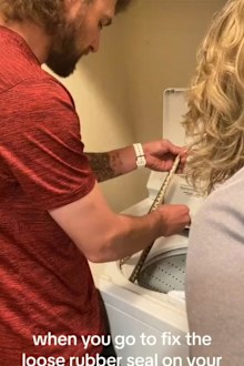 Couple pulls snake from washing machine while fixing loose rubber seal