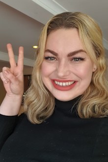 Alita Brydon, woman smiling with a peace sign