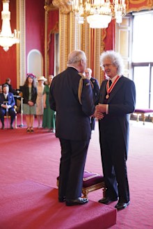 Brian May receiving his knighthood from King Charles at Buckingham Palace