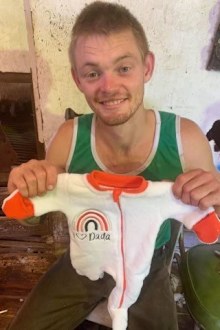 Tom holding a onesie
