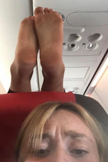 Plane passenger puts dirty feet on woman's headrest