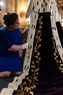 Curator Sally Goodsir makes final adjustments to The Queen's Robe of Estate in a special Coronation display for visitors to the Summer Opening of Buckingham Palace.