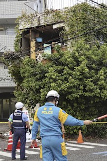 Police stand outside a damaged building following an earthquake in Miyazaki.
