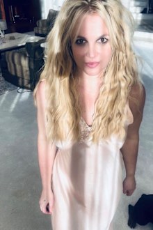 Britney Spears standing in beige dress looking directly at camera