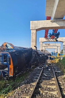 Rescue workers stood on top of overturned railways carriages, some of them with gaping holes torn on their sides, 