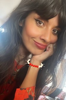 Jameela Jamil wearing red and black, smiling at camera
