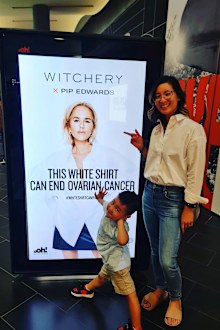 Candice Hung with "life-saving" son Micah, posing in front of a Witchery White Shirt Campaign poster.