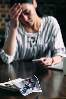 Woman misses ex boyfriend, whose photo is crumpled on the table