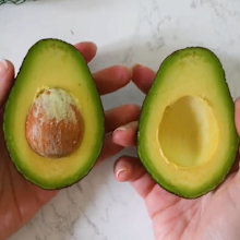 Perfectly ripe avocado cut in half held in hands