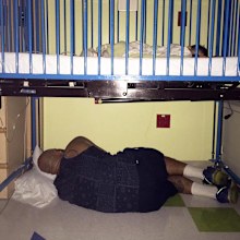 A devoted dad sleeping under the hospital cot of his sick son. (Facebook/Amy Palmer)