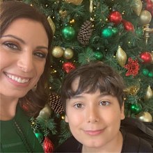 Jo Abi and her son standing in front of a Christmas tree