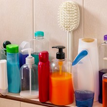 Many shampoo and soap bottles on a bathroom or shower shelf.