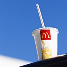 McDonalds cup sitting on ledge, blue sky in background