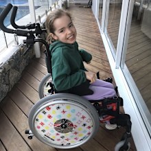 Eva Kalpidis grins sitting in her wheelchair.