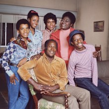 Good Times cast members (left to right) Raplh Carter (as Michael Evans);  BernNadette Stanis (as Thelma Evans Anderson);  Ja'net DuBois (as Willona Woods);  John Amos (as James Evans);  Esther Rolle (as Florida Evans)  and Jimmie Walker (as James Evans, Jr. / J.J.). 1975. Copyright CBS Worldwide Inc. All Rights Reserved. Credit: CBS Photo Archive.