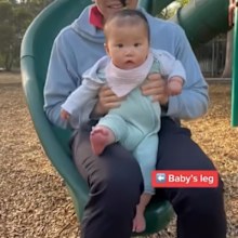 Dad going down slide with baby. 